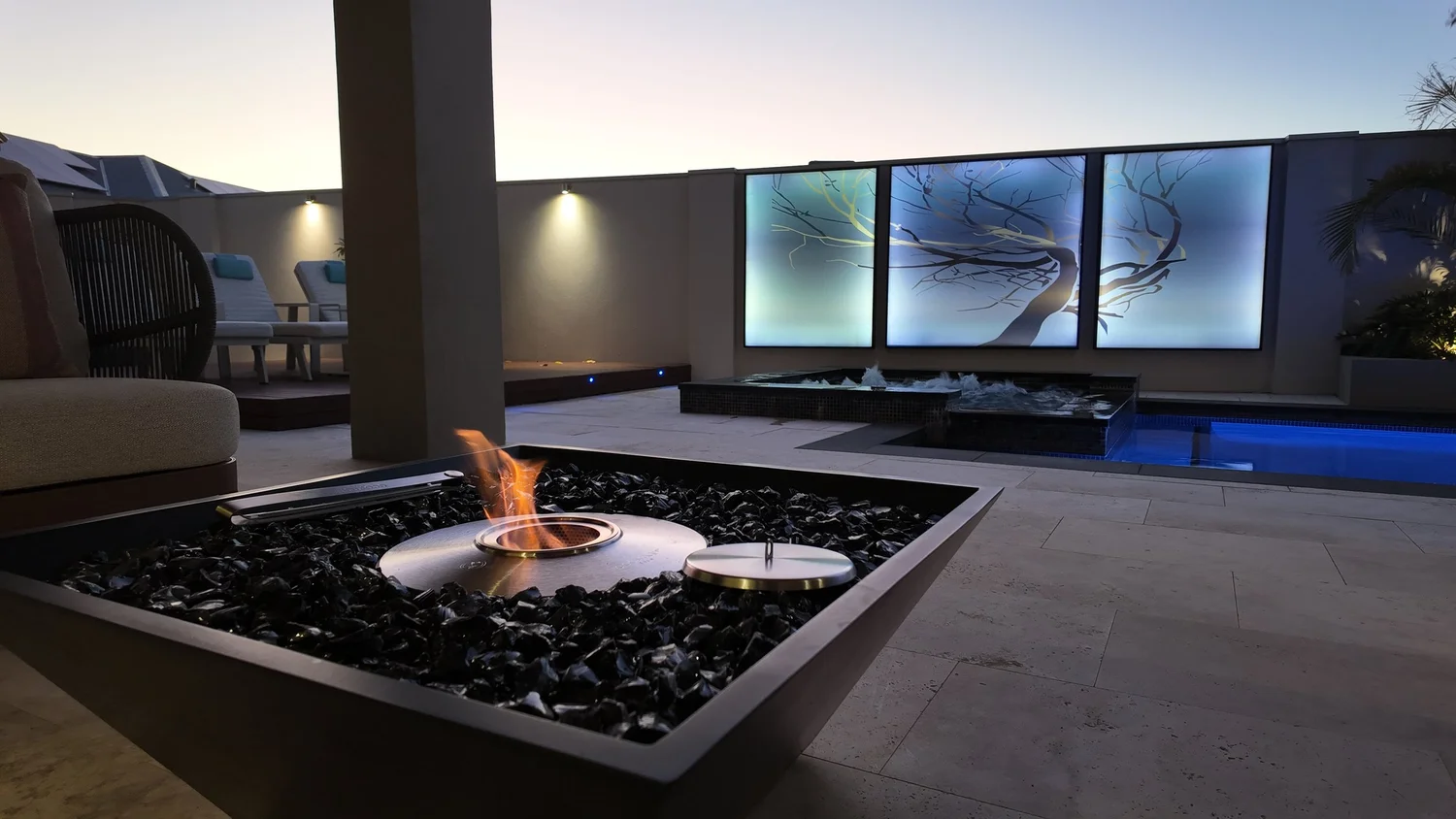 Fire pit and infinity spa lit at dusk